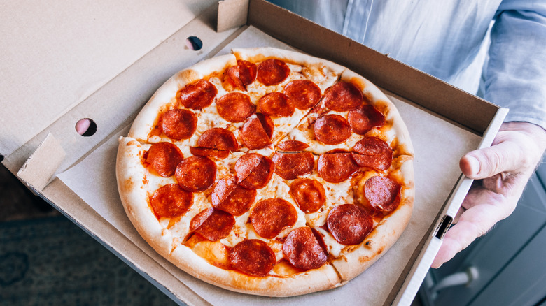 Man holding a box of pepperoni pizza