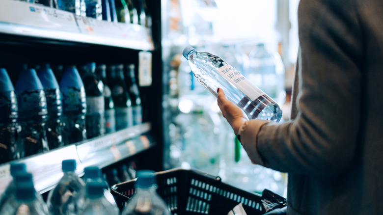 picking up a bottled water from the shelf at a grocery store