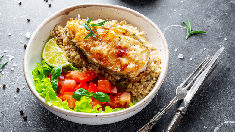 rice bowl with catfish steak on black surface