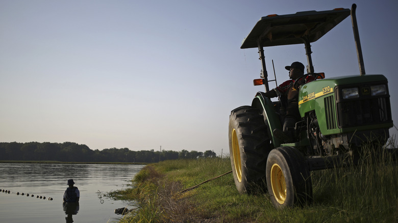 man in John Deree truck by catfish farm