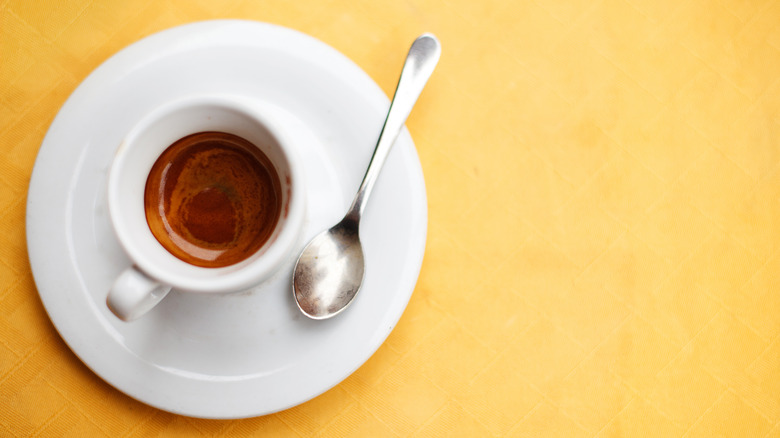 Demitasse spoon with espresso on a yellow table