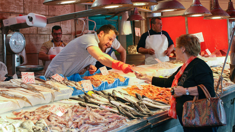 A woman purchases fish from a market stall