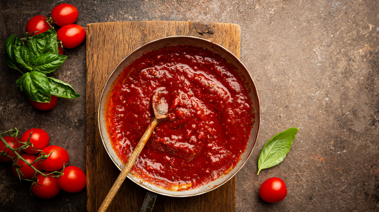 salt, tomatoes, cutting board, pot of Sunday sauce