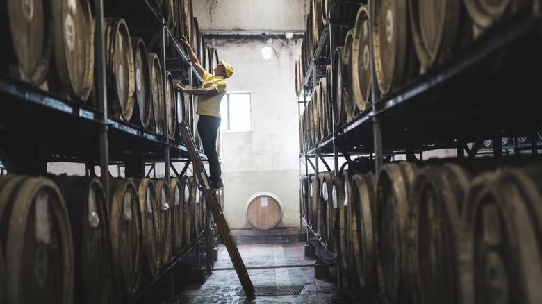 Man on ladder in distillery barrel house