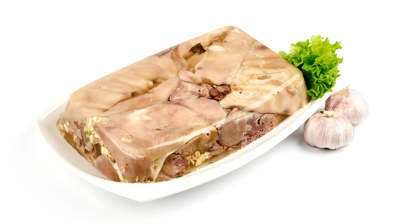 Head cheese with greens and garlic against a white background