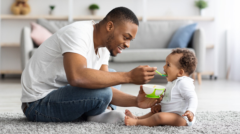 dad feeding a happy baby