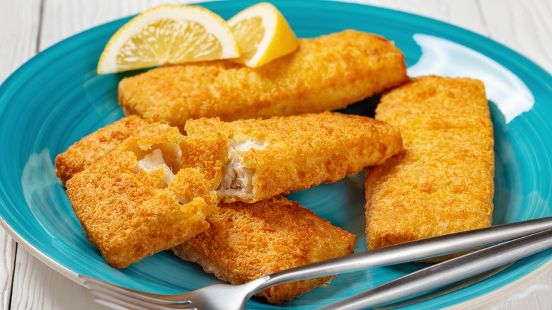 breaded fish sticks with lemon wedges