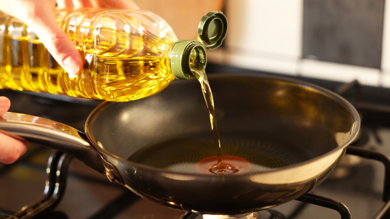 Person pouring cooking oil into a pan