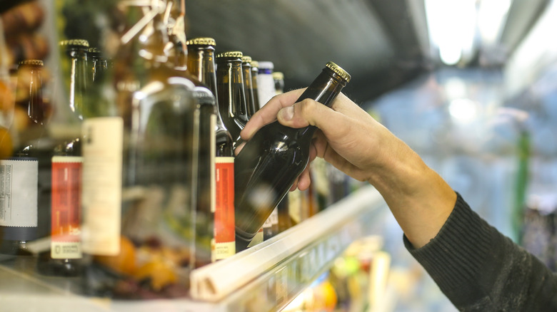 pulling bottle of beer off shelf