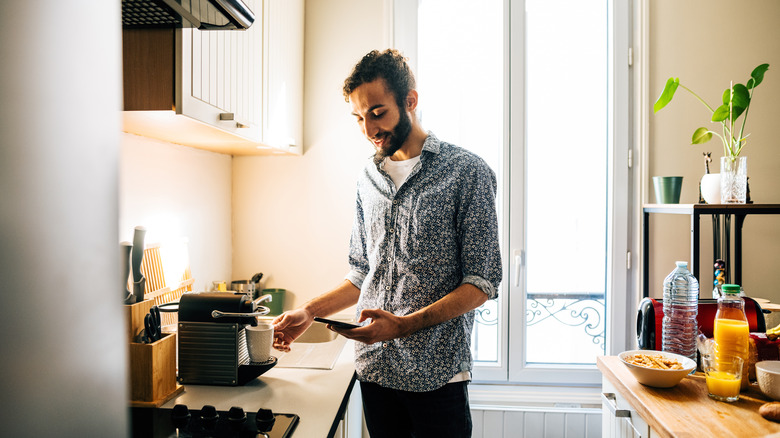 Smiling man brewing coffee with a small coffee maker