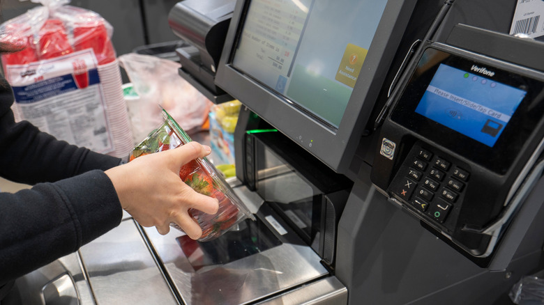 woman self checks out with strawberries