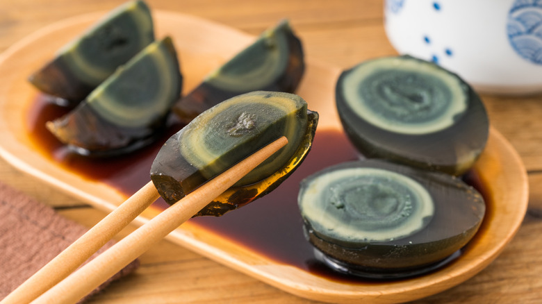 Chopsticks holding a century egg