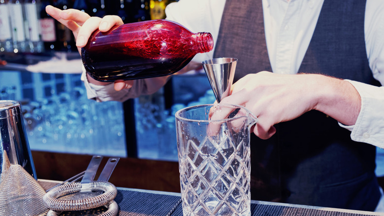 Bartender assembling a cocktail with black currant shrub