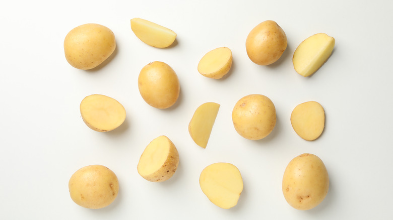 whole, halved, and quartered new potatoes on white background