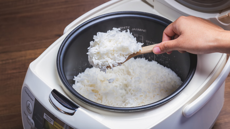 Hand scooping rice from rice cooker