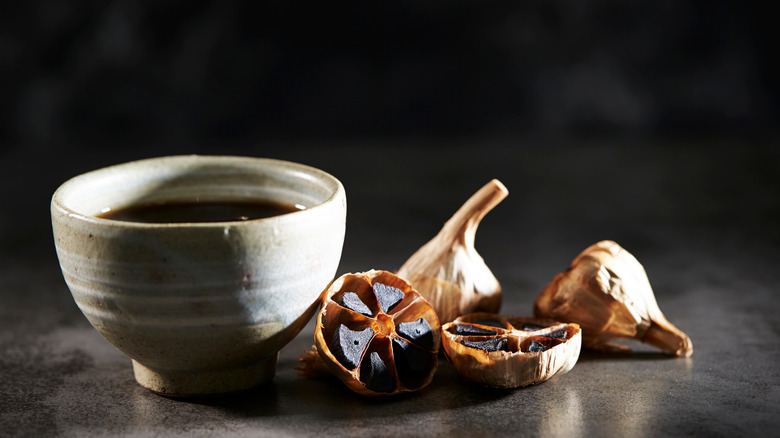 black garlic cloves next to vinegar in bowl