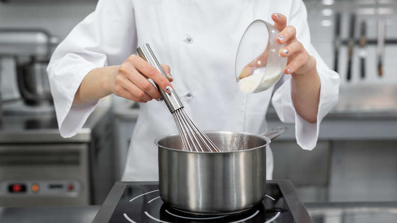 Chef adds sugar to sauce pan