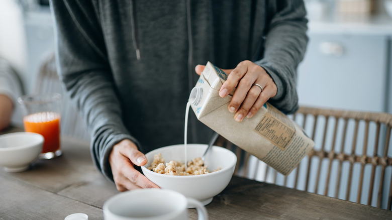 Person pouring milk into cereal