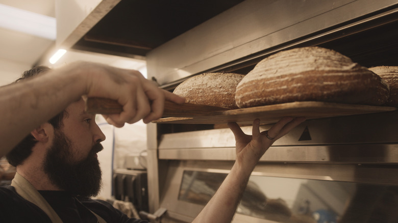 Man removing bread from oven