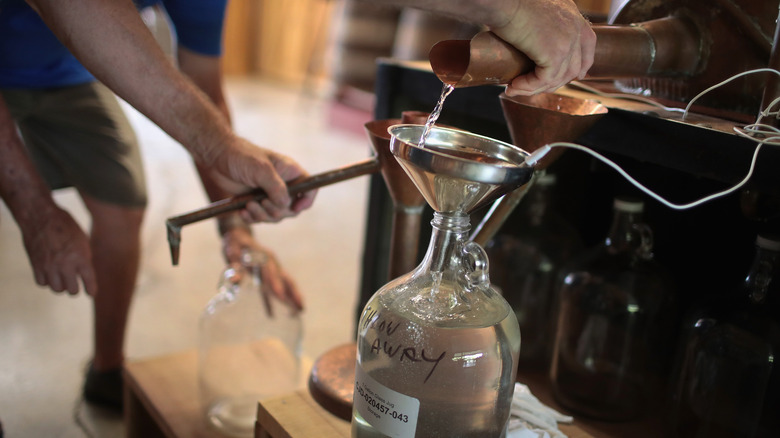 Moonshine being decanted into a glass jug