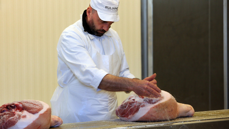 A man hand salting meat to cure it