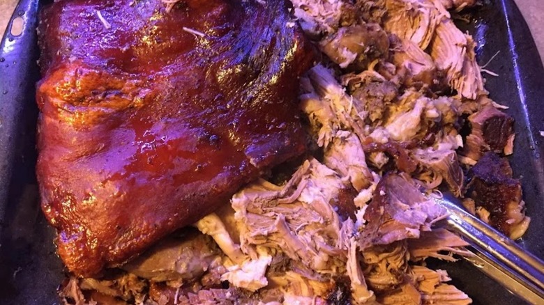 both whole and shredded pernil in a roasting pan