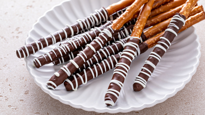 Chocolate-dipped pretzel rods on a white plate