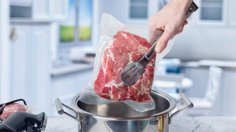 Hand lowering sous vide beef into pot