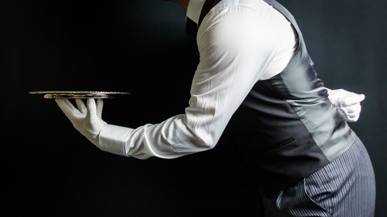 A butler holds out a silver tray