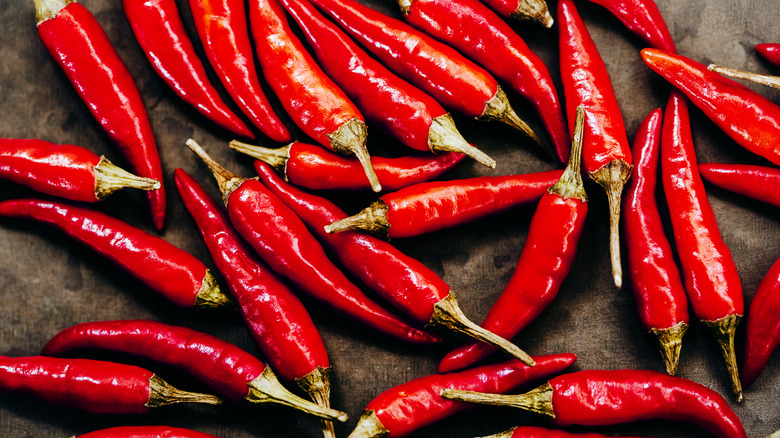 Dozens of red hot chili peppers scattered on a black background