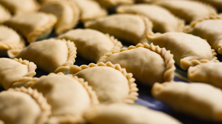 unbaked empanadas in a row