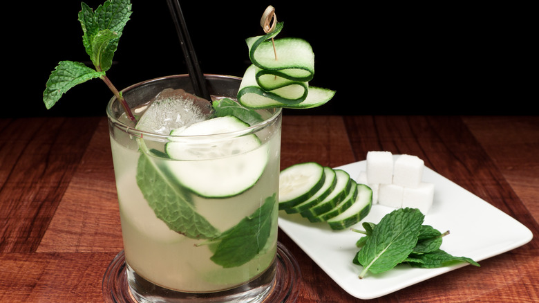 cocktail glass with with slices of cucumbers and mint leaves