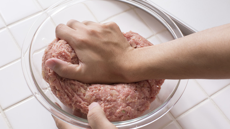 Hand kneading meat and onion mixture