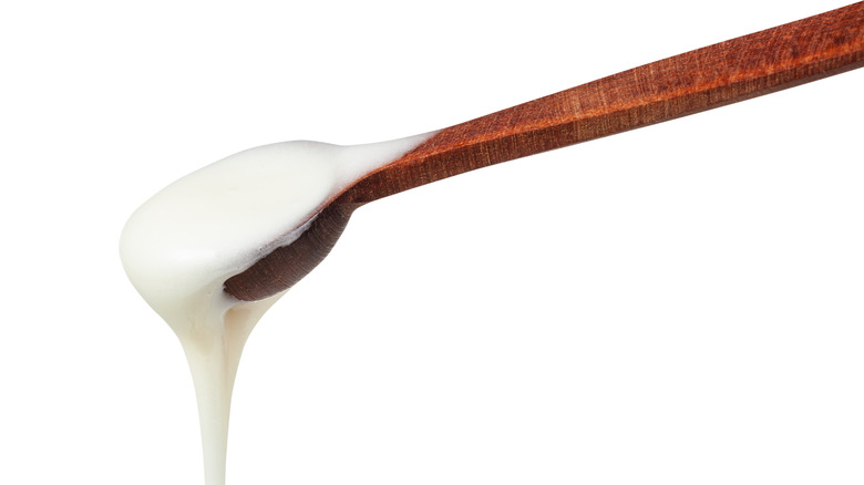 Wooden spoon dripping white honey