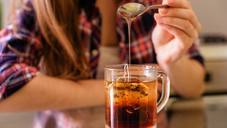 Woman adding honey to tea