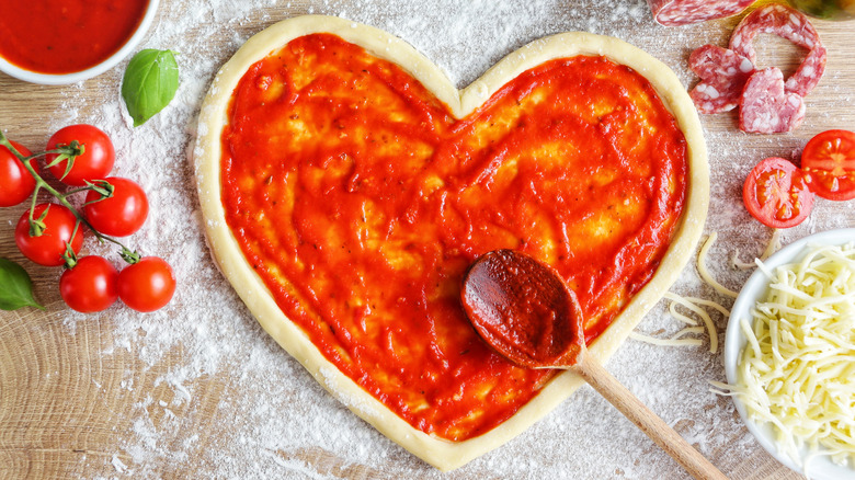 Heart-shaped pizza with red sauce.