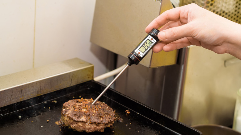 Checking hamburger with a thermometer