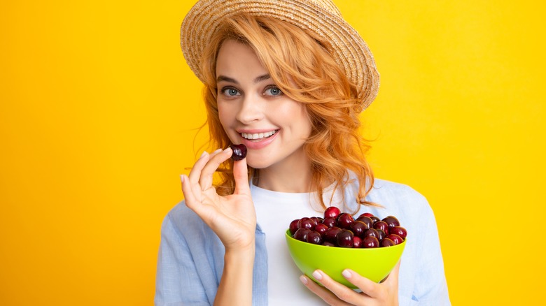 women holding bowl of cherries
