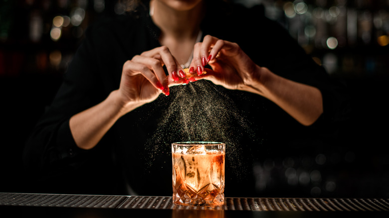 bartender garnishing drink with orange peel