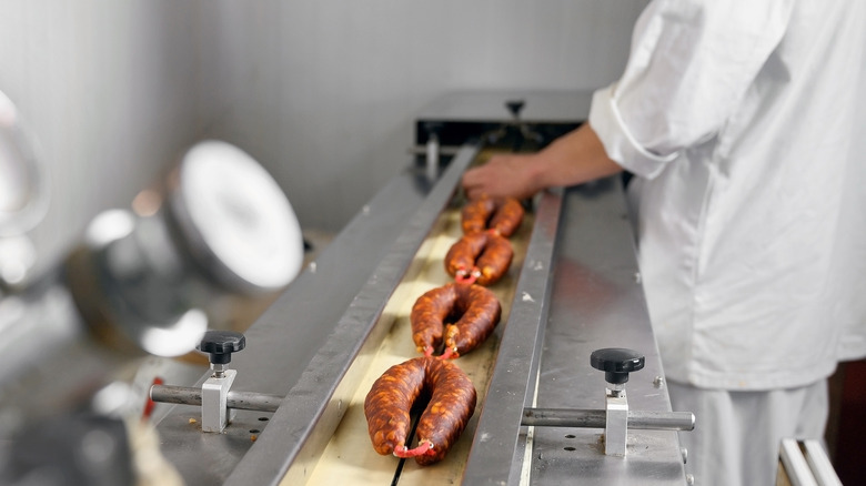 Sausages being cased on a conveyor belt 