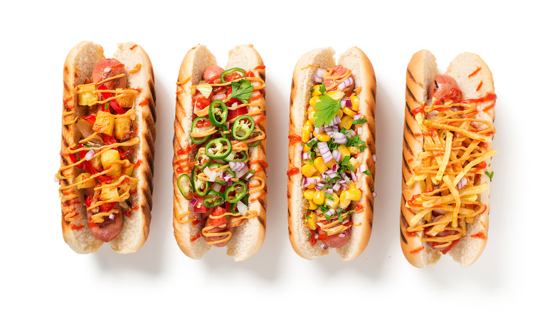 Four hot dogs with colorful toppings.
