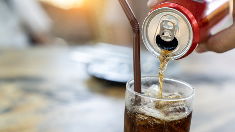 Soda being poured into a glass of ice