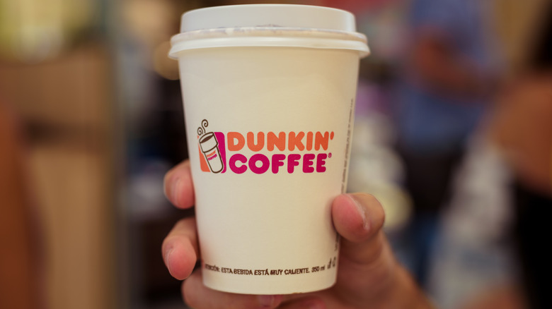 Hand holding cup of Dunkin' coffee