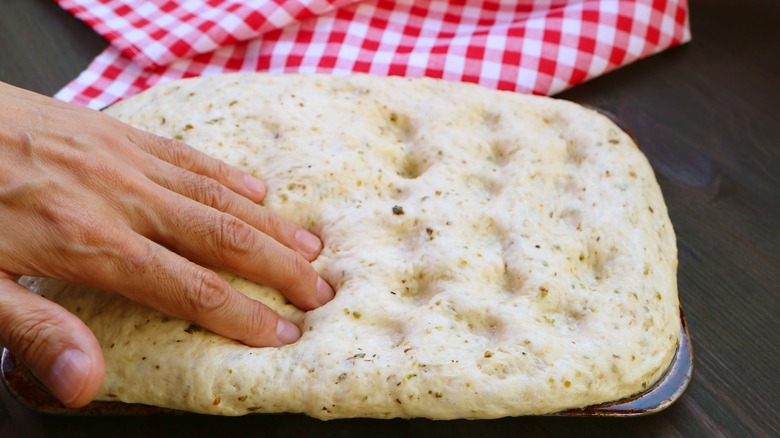 fingers dimpling focaccia bread dough