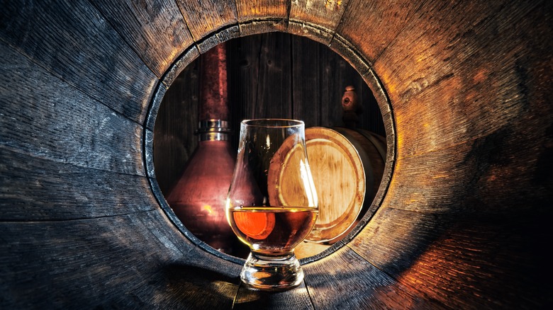 A glass of whiskey inside a barrel