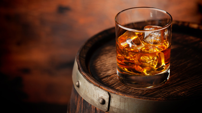 glass of bourbon on a barrel