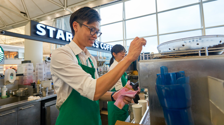 Two Starbucks employees wearing green aprons