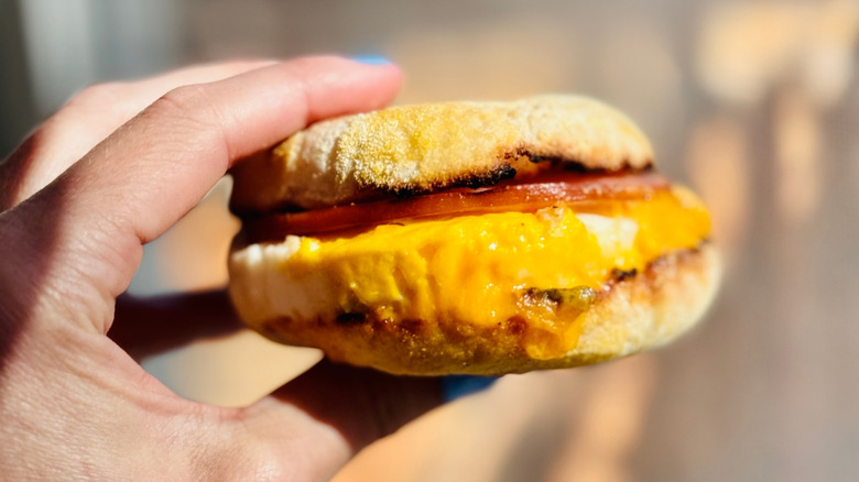 woman holding egg mcmuffin breakfast sandwich