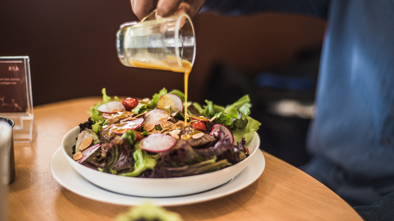 vinaigrette being drizzled onto salad