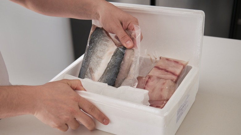 man taking frozen fish out of box